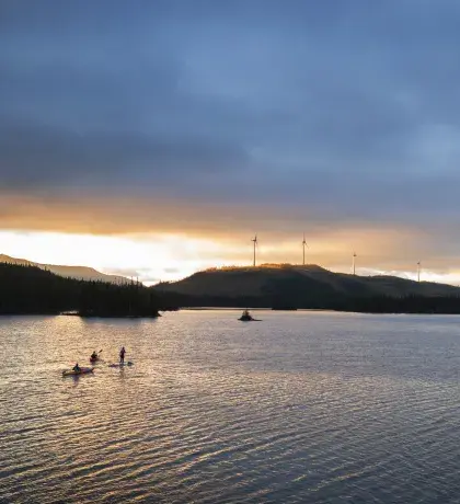 Kayakiste sur lac et éoliennes en fond