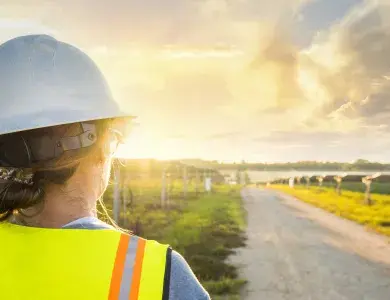 Technicienne faisant face à des panneaux solaires et un couché de soleil