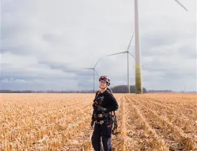 Technicienne éolien Boralex dans un champ face à une éolienne au Canada