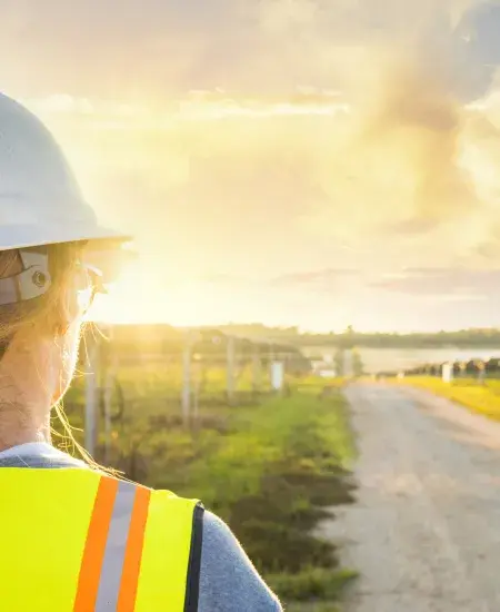 Technicienne faisant face à des panneaux solaires et un couché de soleil