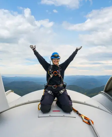 Employée sur le toit d'une éolienne levant les bras